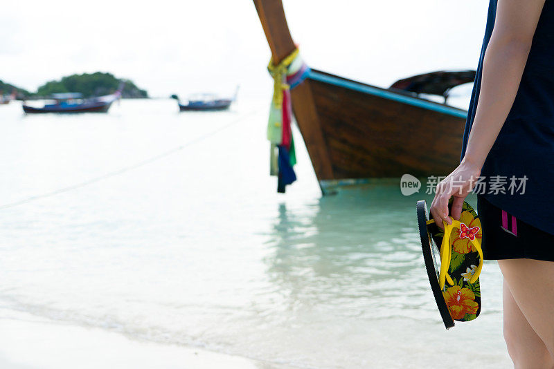 海滩旅行-女孩拿着拖鞋走在白色的沙滩上，度假和放松