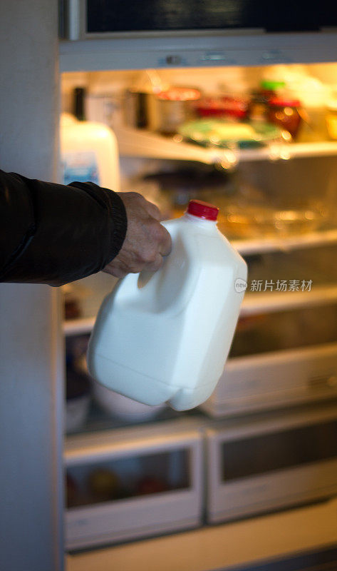 男人把食品杂货(加仑牛奶)放在冰箱里