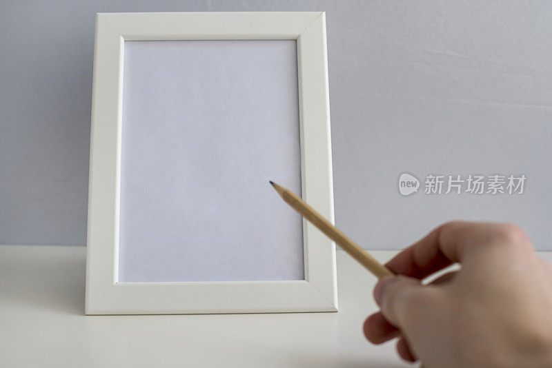 手拿铅笔在白色的画框上画画、写字