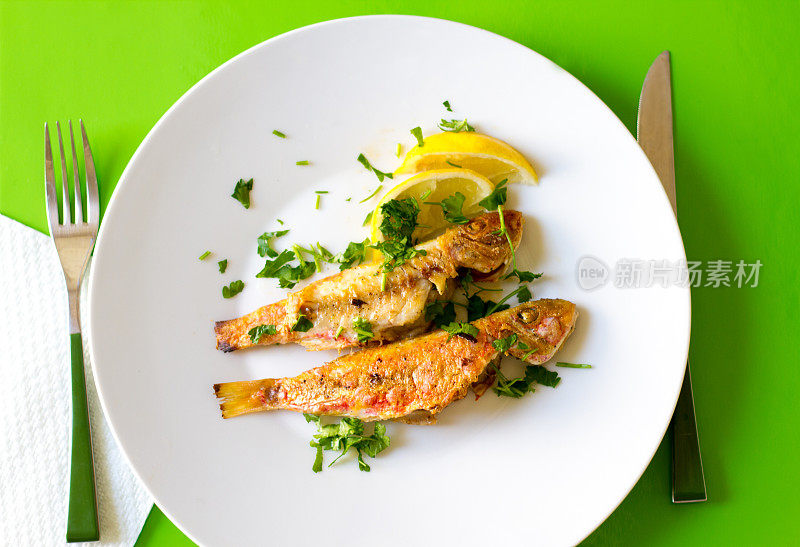 两条炸鱼;柠檬和香菜;绿色背景