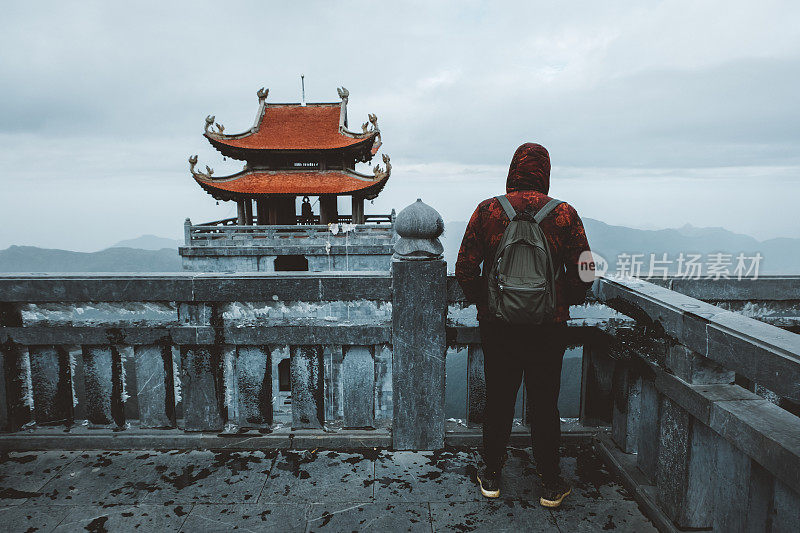 一个背着背包的人在越南看佛教寺庙和雾蒙蒙的山脉