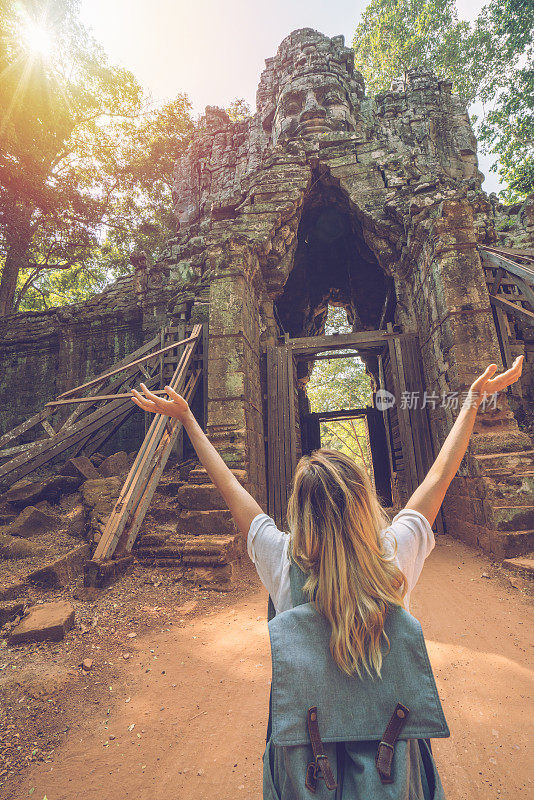 女旅人从寺庙的复杂大门伸出双臂，感受着旅行的自由和幸福