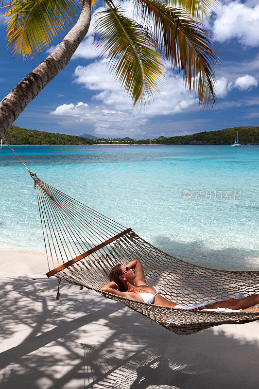 女人放松在一个原始热带海滩的吊床上