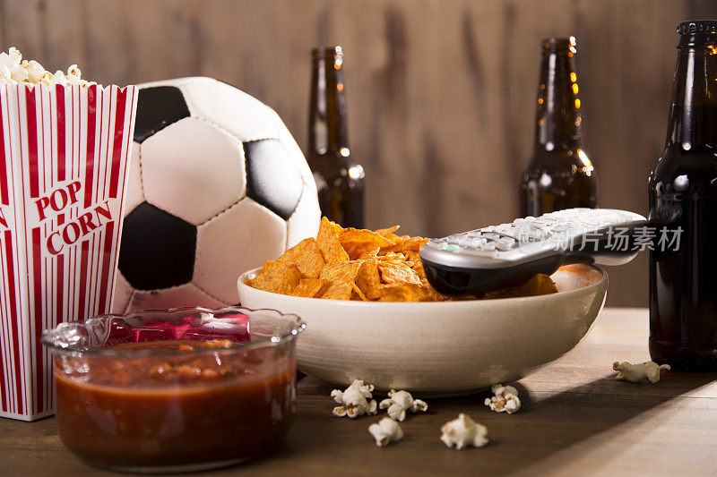 一边看足球比赛一边吃零食，喝饮料。