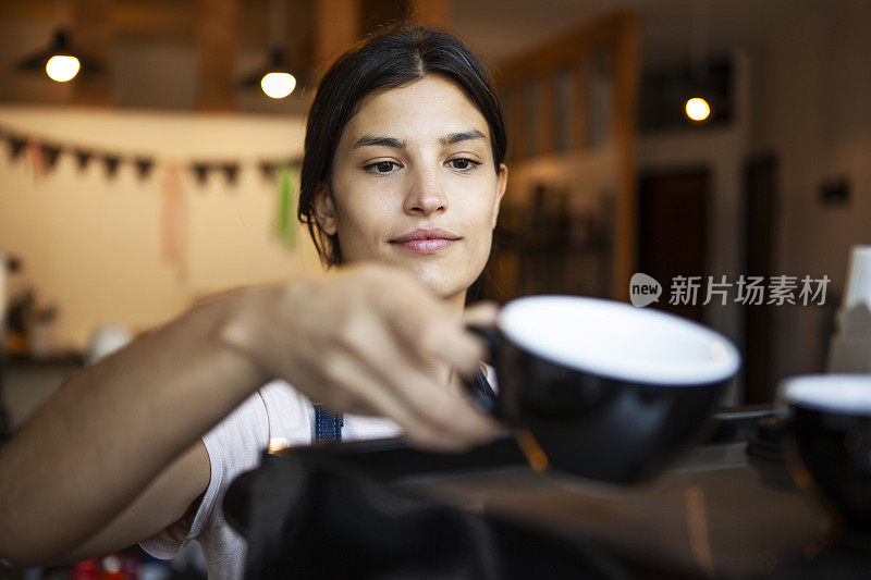年轻微笑的女人在咖啡店准备咖啡
