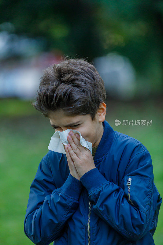 感冒和高烧的生病男孩在户外打喷嚏和咳嗽。