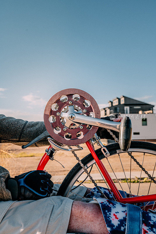 齿轮和手踏板的特写镜头与一个男人的矫形腿支架适应运动的红色自行车