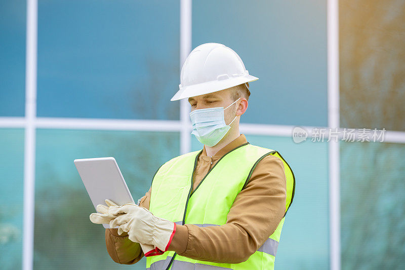 现代商业建筑竣工后，建筑工程师或建筑工人在施工现场使用数字平板电脑
