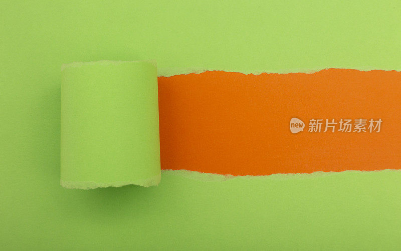 在橙色背景上撕开一个绿色的纸框洞