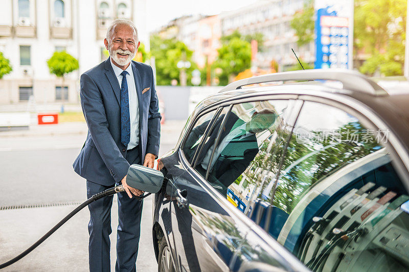 一位老人在加油站给他的车加油。