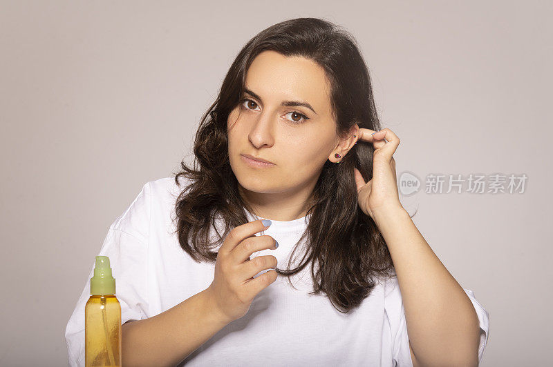 年轻美丽的女人用摩洛哥坚果油按摩头发。