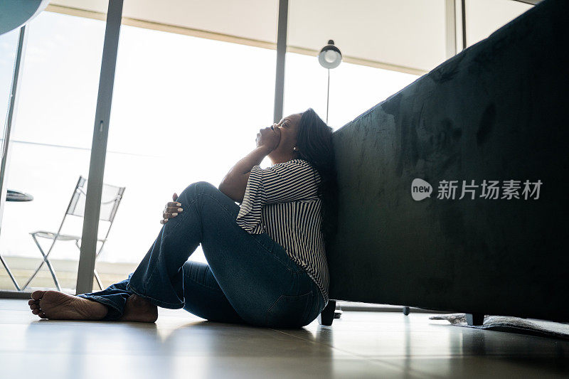 沮丧的成熟女人坐在家里的地上