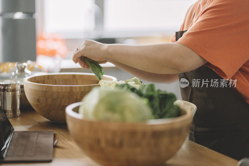 亚洲中国母亲在厨房为准备饭菜削蔬菜皮