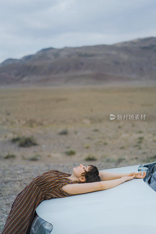 一个女人躺在沙漠里的车上