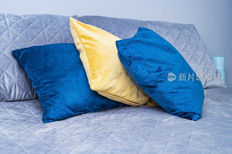 灰色的床罩，亮蓝色的，床上有黄色的枕头。北欧风格。