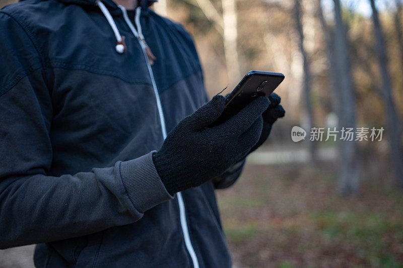 一个面目全非的年轻运动员在森林里用手机