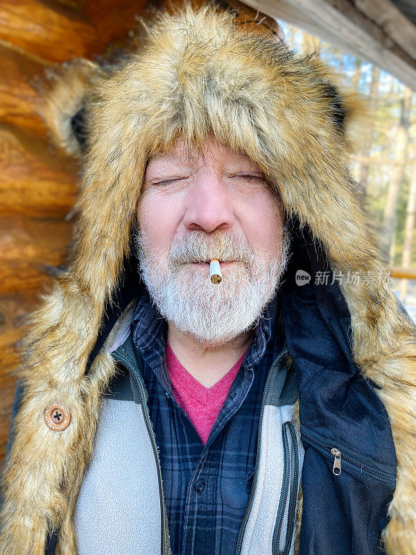 老头戴着一顶大皮帽，手里拿着未点燃的香烟。