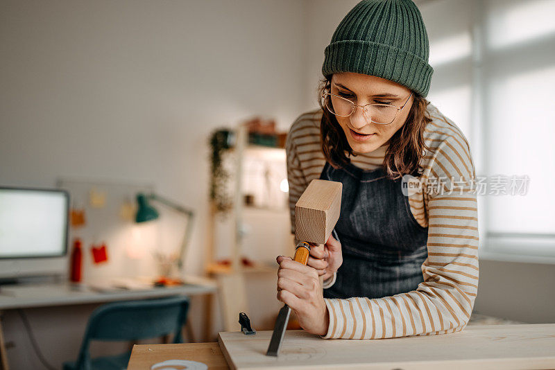 女艺术家在工作室用锤子和凿子雕刻木头