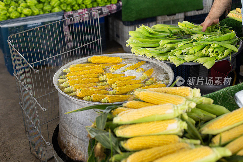 有新鲜有机水果和蔬菜的街市。站在生玉米和煮玉米旁边