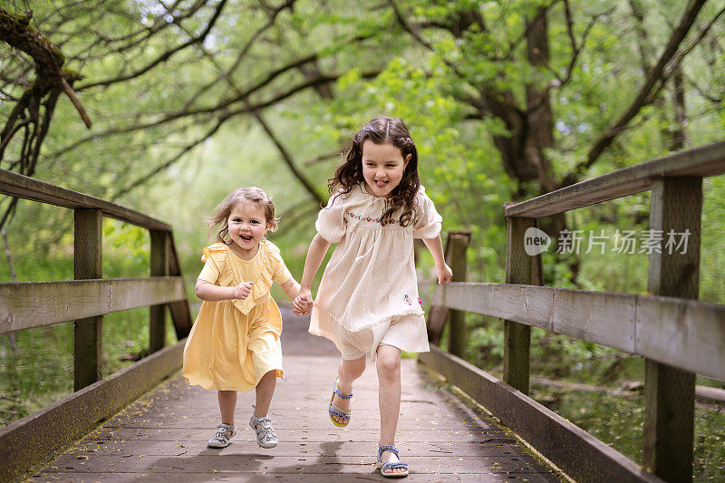 两个可爱的姐妹在外面的森林里奔跑