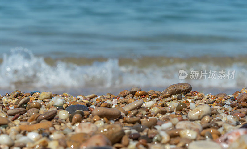 卵石滩上有湿卵石。在海浪和泡沫的背景下。低角度的观点。