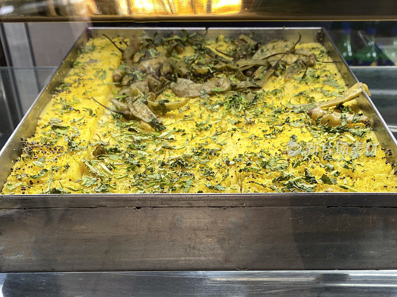 印度商店陈列的Khandvi(辣克面粉卷)的托盘图像，高架视图，关注前景