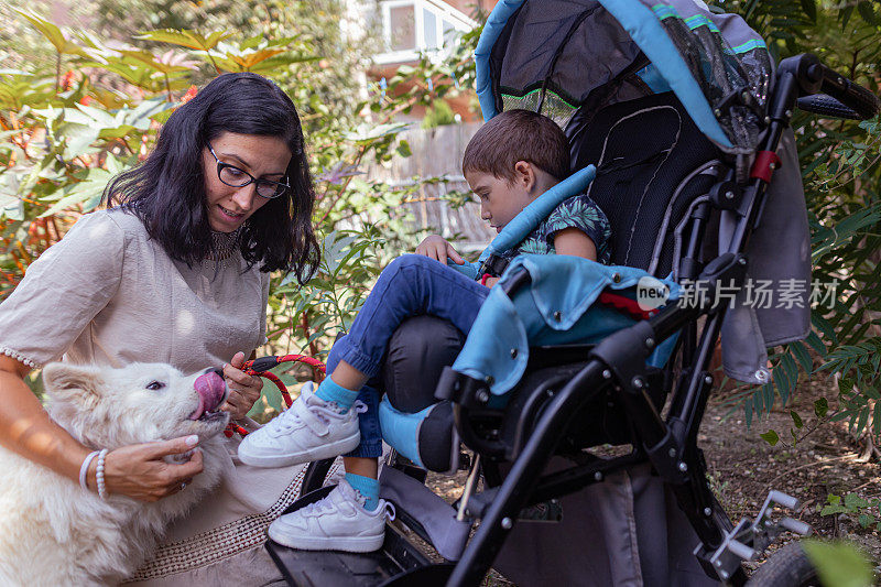 一个女人正在训练一只治疗犬。帮助身体有残疾的小男孩。