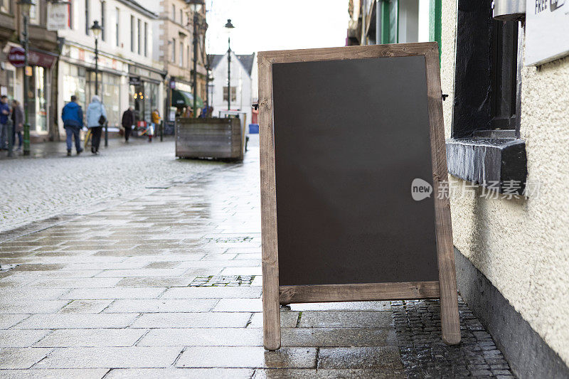 苏格兰商业街潮湿人行道上的空白黑板a框