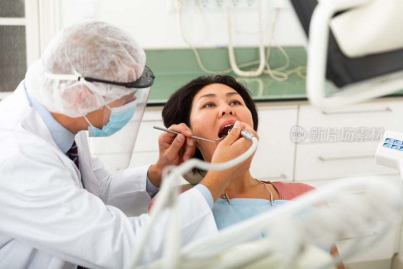 牙医为坐在医疗椅上的女病人补牙