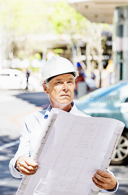 戴着安全帽手持建筑图则的土木工程师、建筑工人、建筑师或经理