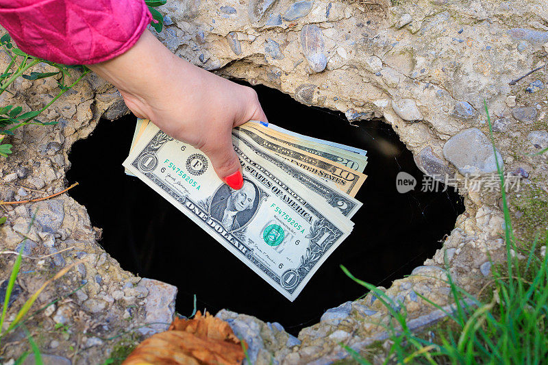 那只手把美元扔进混凝土的黑洞里。浪费金钱的抽象概念