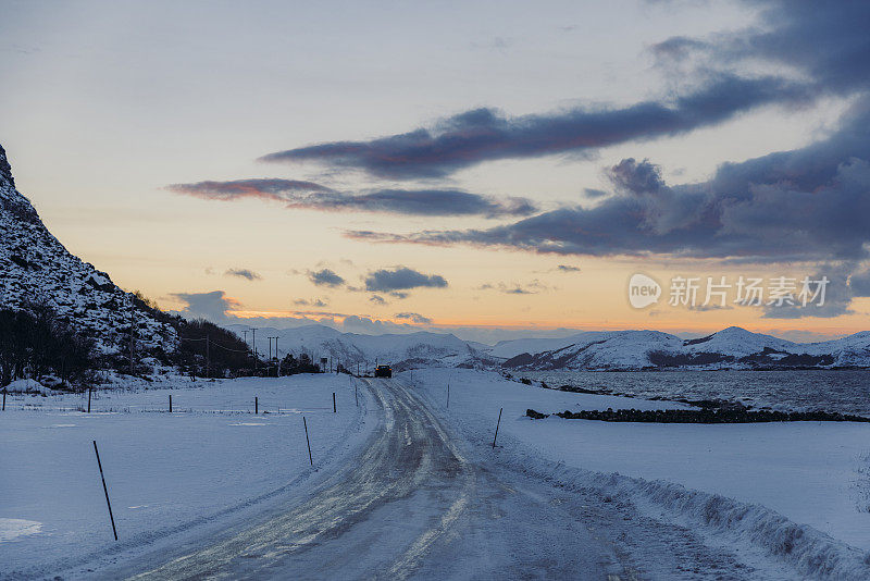 风景如画的冬季日落在山上与汽车行驶在挪威的道路