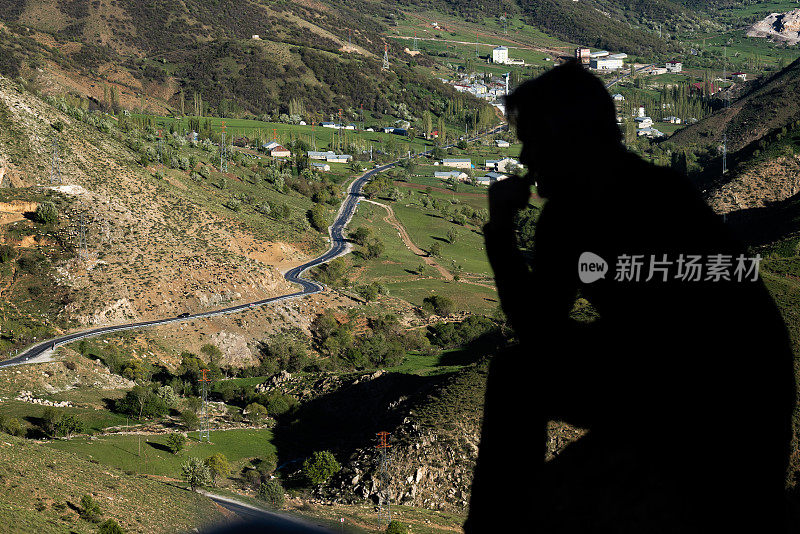 从山顶向被高山包围的小镇望去的人的剪影。