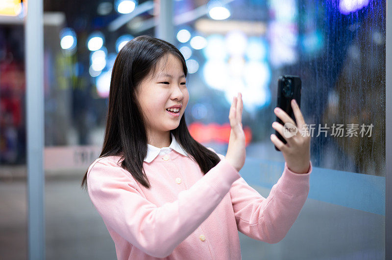 亚洲女孩晚上在城市街道上使用智能手机