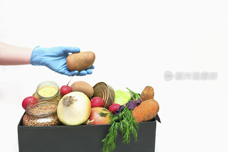 供应食品帮助盒蔬菜，谷物，罐头，鸡蛋和水果。志愿者戴着医用防护手套，带着为冠状病毒慈善机构捐赠的产品，被隔离在复制空间。