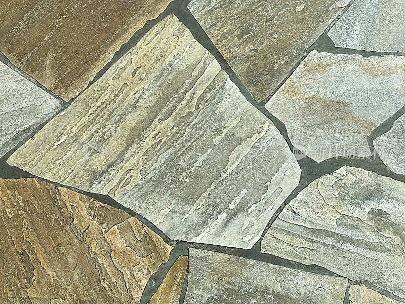 近距离图像铺成的鹅卵石花园天井，不规则的石板路径，不均匀的形状和大小，用水泥填充的平坦石块混合物