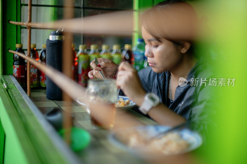 亚洲女孩在小摊上吃印尼传统早餐