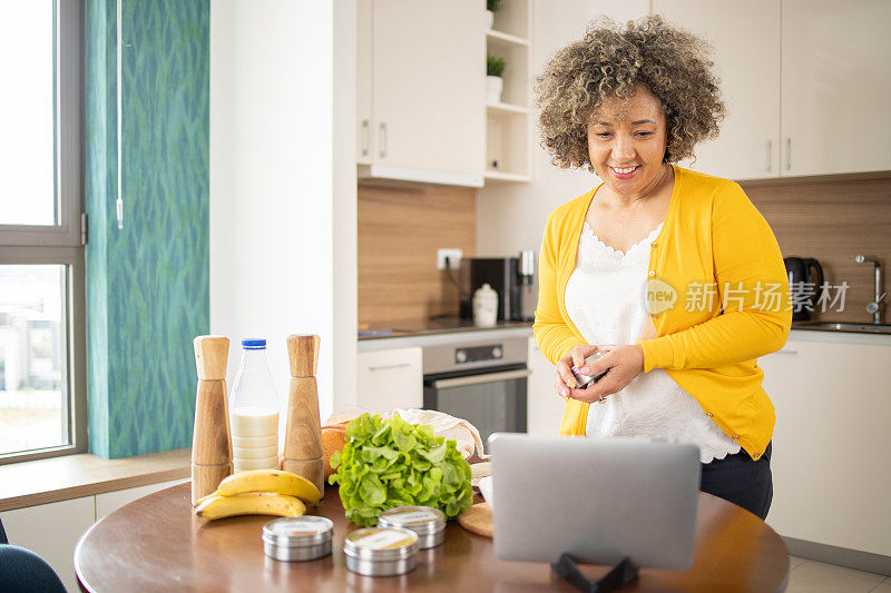 快乐的成熟女人正在厨房里准备一顿健康的饭菜