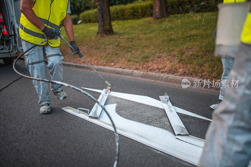 道路维修工人正在喷漆右转路标