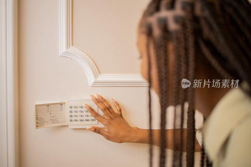 年轻女子用墙上的装置调节家里的温度