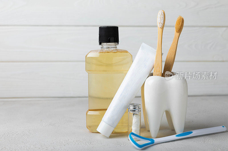 口腔卫生用品和牙齿模型在一个白色的木制背景。白色背景上的牙刷、牙膏和漱口水。牙科保健概念。口腔卫生。口腔护理理念。本空间