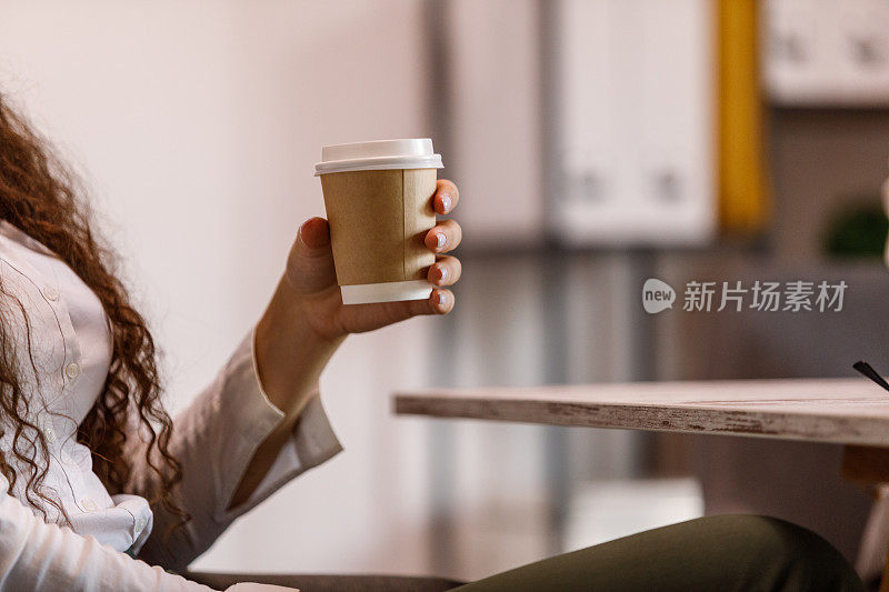 一个女商人拿着一次性咖啡杯的快照