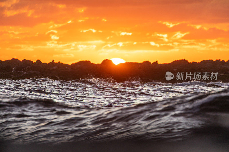 日出在海岸岩石上，海浪荡漾