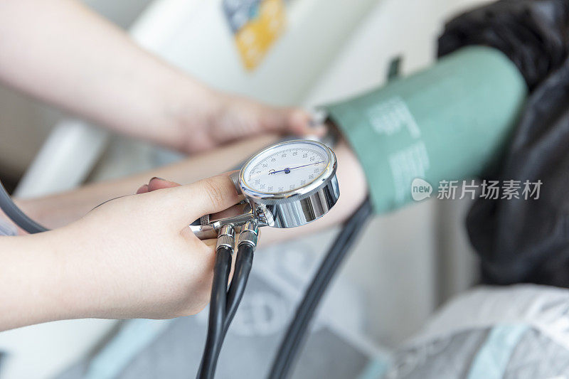 女护士在她的房间测量女病人的血压。