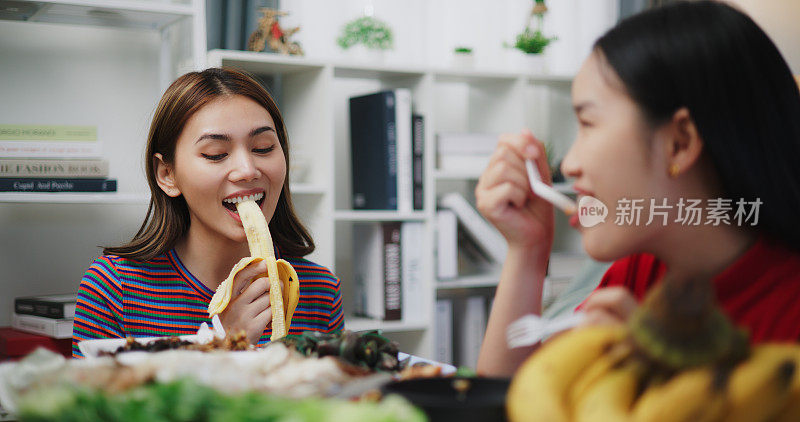 快乐的年轻亚洲女人坐在家里客厅的地板上吃泰国菜