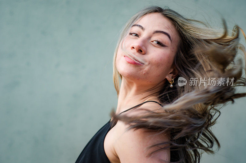 美丽的年轻女子的肖像玩她的头发在灰色背景