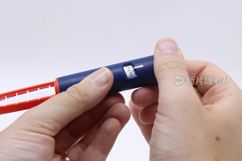 一名妇女拿着胰岛素笔，选择病人需要注射多少胰岛素