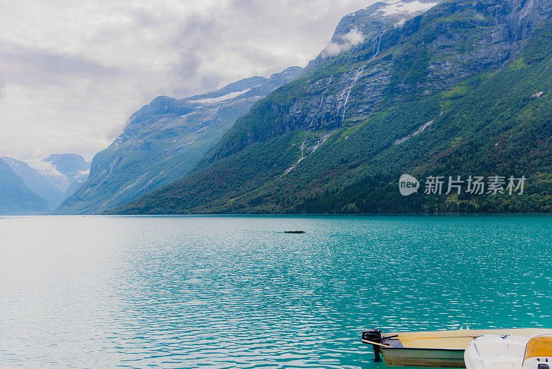 田园诗般的夏季景观与船在水晶蓝湖与山景在挪威