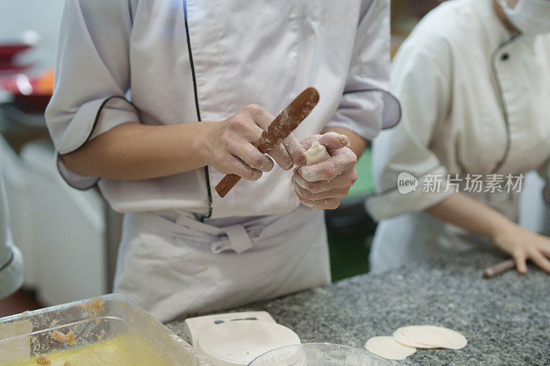 熟练的厨师在餐厅的开放式厨房里包小笼包。