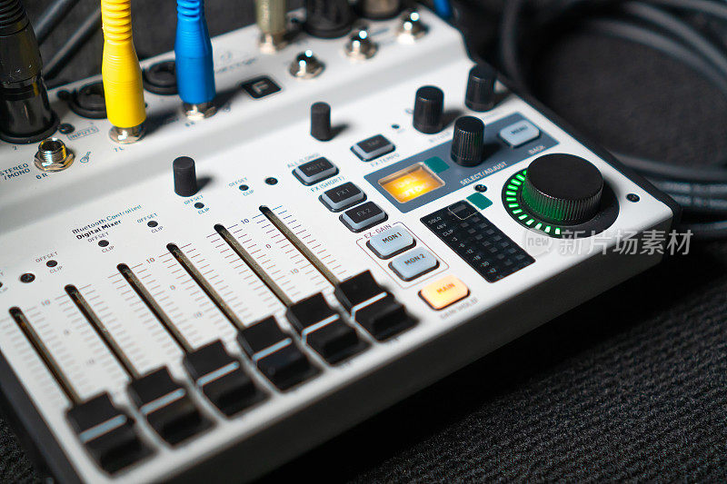 近距离图像的手调节混音旋钮的音量控制在现场演播室的表现。Mixer具有多个旋钮和按钮，用于精确的音频混合调整。